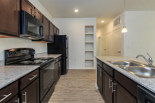 a kitchen with stainless steel appliances granite countertop a sink stove microwave refrigerator and cabinets