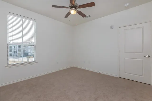 an empty room with a window and a fan