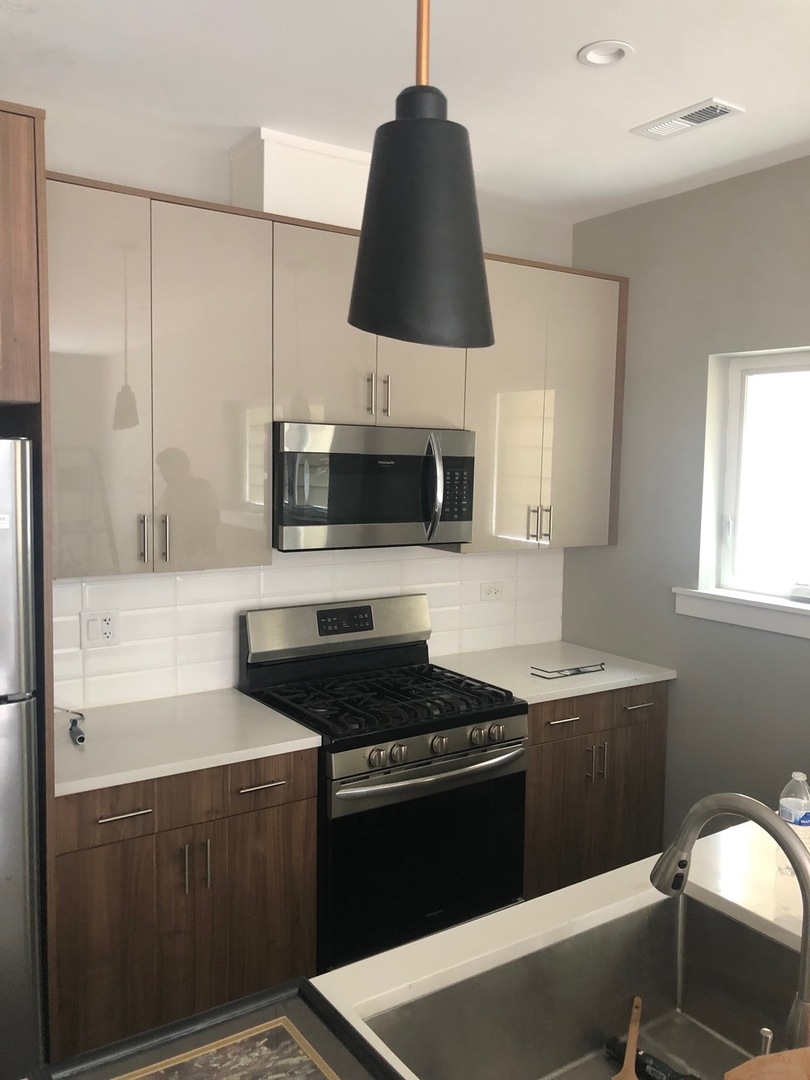 1734 West Cullerton Street, Unit 1 Chicago, IL 60608 - Photo 2 of 12 a kitchen with granite countertop a sink a stove and microwave