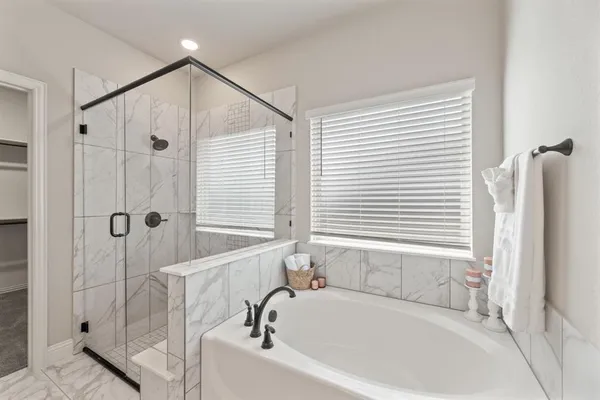 a spacious bedroom with a large bed a chandelier and windows