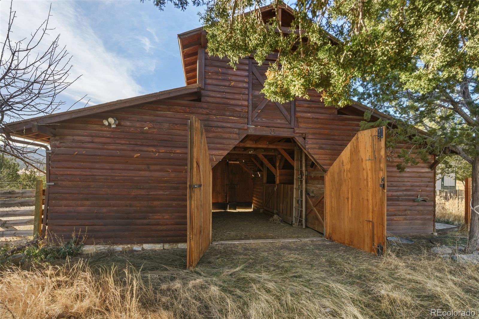 2925 Siloam Road Pueblo, CO 81005 - Photo 34 of 44 a view of a wooden house with a large tree and wooden fence