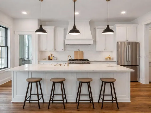 a kitchen with stainless steel appliances granite countertop a sink a stove a refrigerator and island with wooden floor