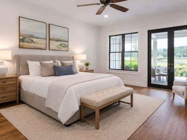 a spacious bedroom with a bed a table and three large window