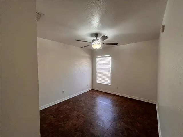 a view of an empty room with a chandelier fan and a window