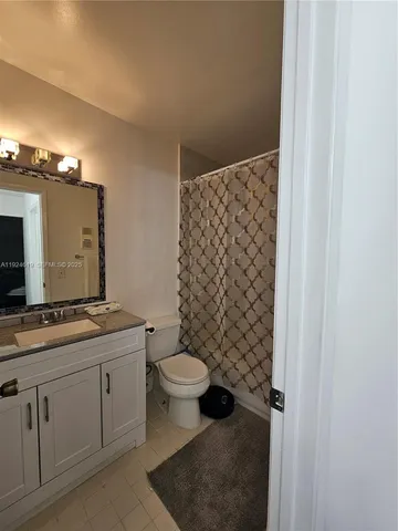 a bathroom with a granite countertop sink toilet and mirror