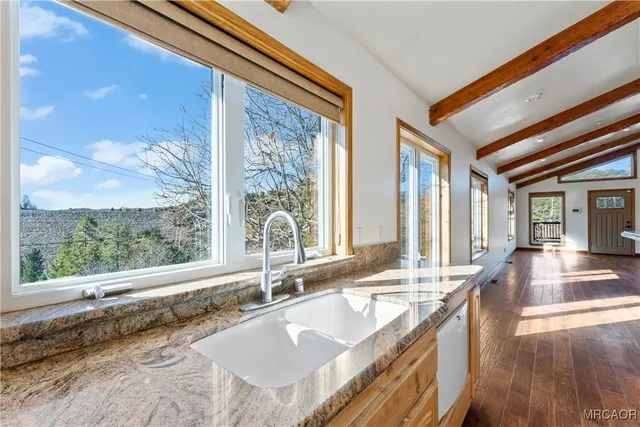 a kitchen with stainless steel appliances granite countertop a sink dishwasher stove and white cabinets with wooden floor