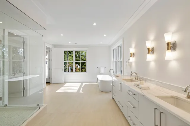 a spacious bathroom with a double vanity sink a large mirror and a shower