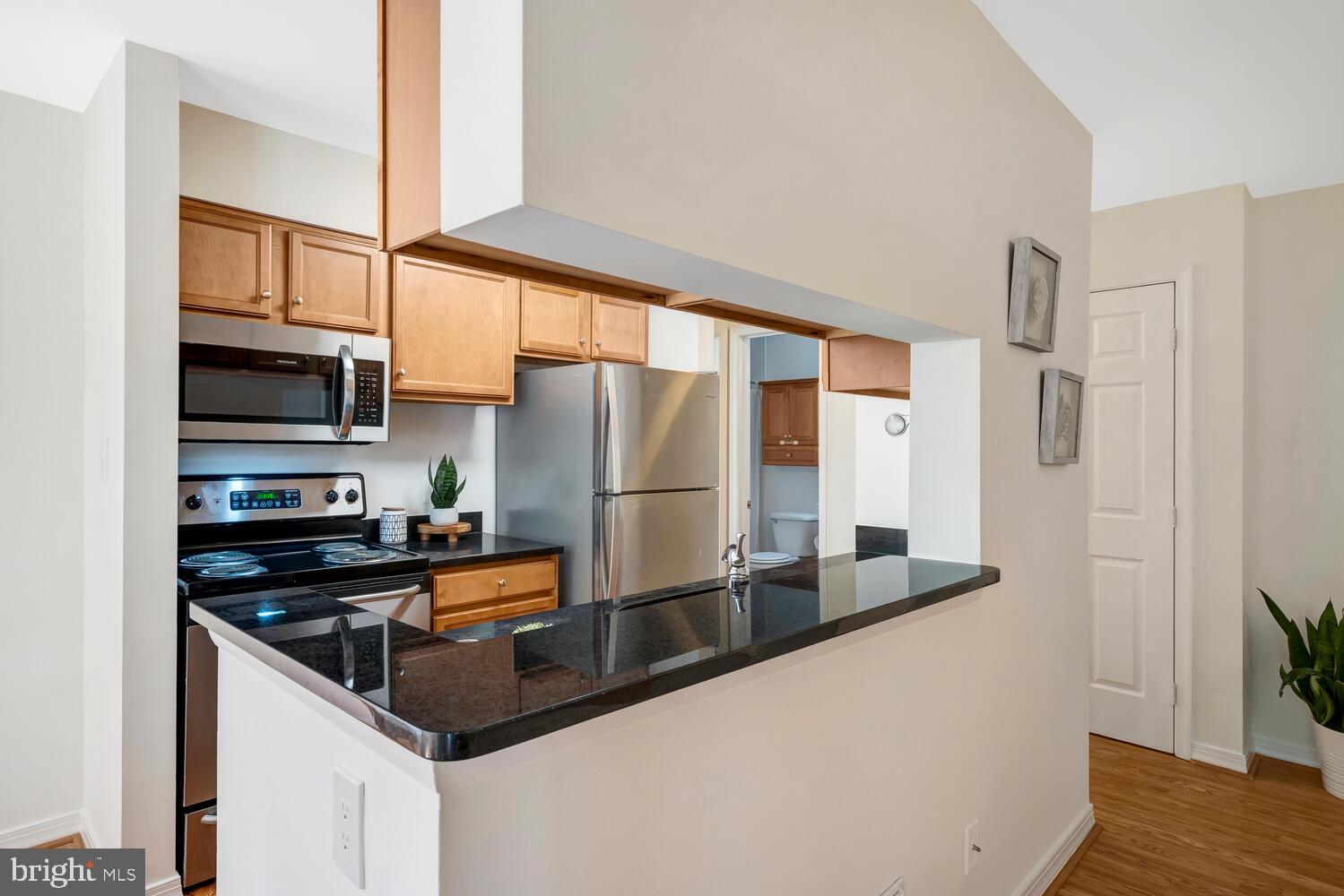 1791 Jonathan Way, Unit 1791C Reston, VA 20190 - Photo 14 of 58 a kitchen with stainless steel appliances granite countertop a refrigerator a stove and a sink with wooden floor