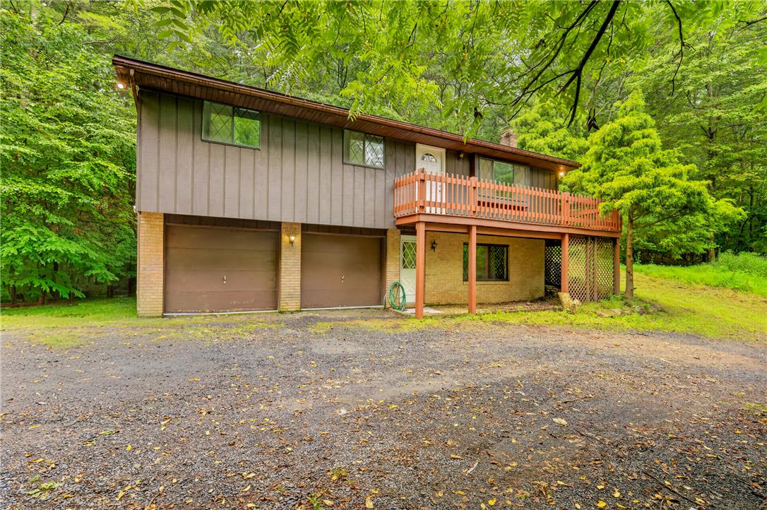 1570 Astolat Road Effort, PA 18330 - Photo 2 of 48 Mature trees frame a rustic home featuring vertical wood siding, brick accents, and a spacious deck.