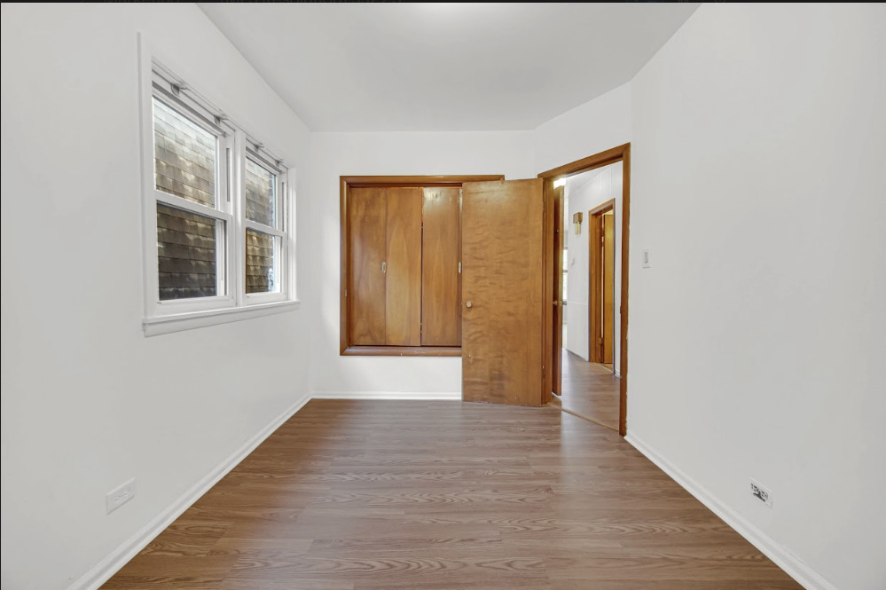 3329 South Racine Avenue Chicago, IL 60608 - Photo 19 of 33 a view of an empty room with wooden floor and a window