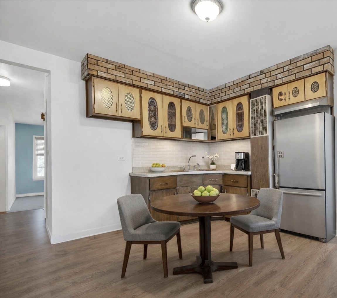 3329 South Racine Avenue Chicago, IL 60608 - Photo 8 of 33 a kitchen with stainless steel appliances granite countertop a stove top oven a refrigerator a dining table and chairs with wooden floor
