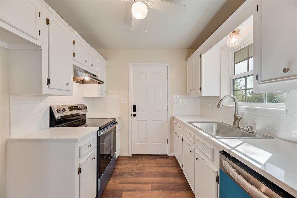 751 County Road 1240 Mount Pleasant, TX 75455 - Photo 22 of 35 a kitchen with granite countertop a sink dishwasher stove and white cabinets with wooden floor