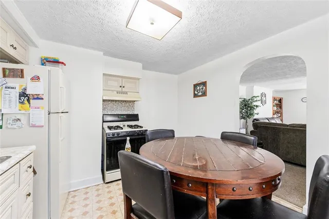a kitchen with refrigerator a stove a dining table and chairs