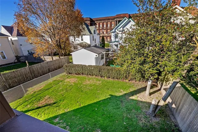 a view of a backyard with couches plants and large trees