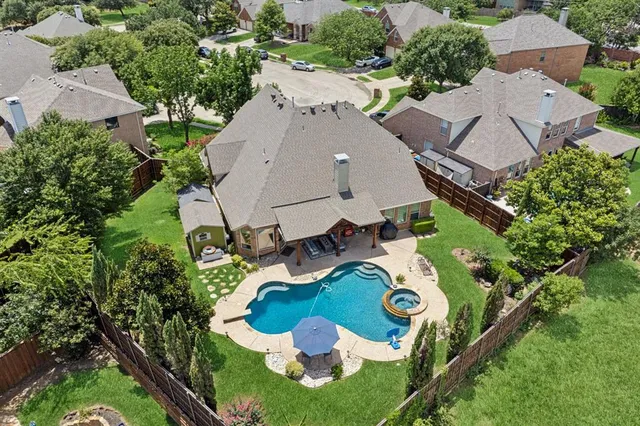 an aerial view of a house with swimming pool and large trees