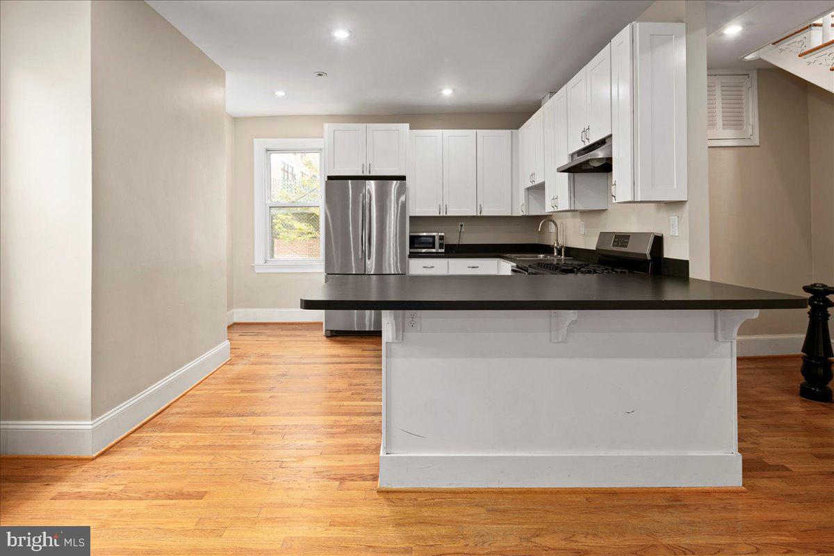 304 2nd Street Southeast Washington, DC 20003 - Photo 36 of 70 a kitchen with stainless steel appliances granite countertop a refrigerator a sink dishwasher a stove and white countertops with wooden floor