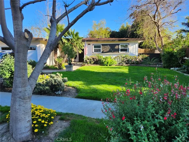 a front view of a house with a yard and potted plants