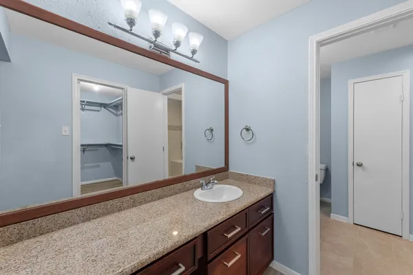 a bathroom with a granite countertop sink a mirror and a shower