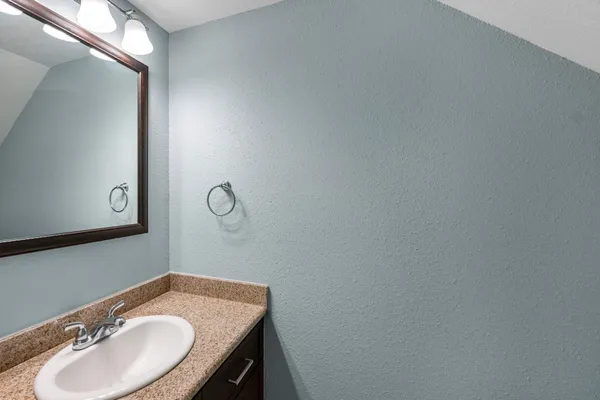 a bathroom with a granite countertop sink and a mirror