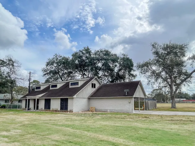 a white house with a big yard and large trees