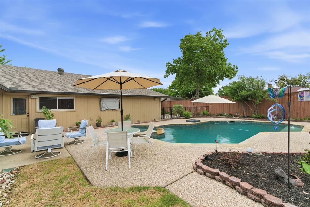 2307 Castle Rock Road Carrollton, TX 75007 - Photo 30 of 34 The property features an outdoor swimming pool, a spacious patio area, and a fenced yard with mature trees