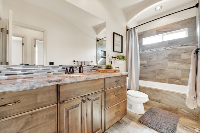 302 Old Farm Road Tooele, UT 84074 - Photo 12 of 30 Bathroom featuring a wood-finish double vanity with a light-toned countertop, mosaic tile backsplash, and bronze-finish fixtures