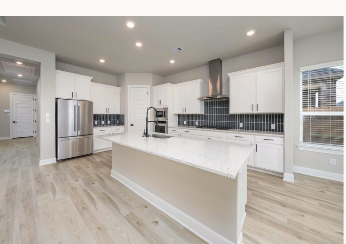 a kitchen with stainless steel appliances kitchen island granite countertop a stove a sink and white cabinets with wooden floor