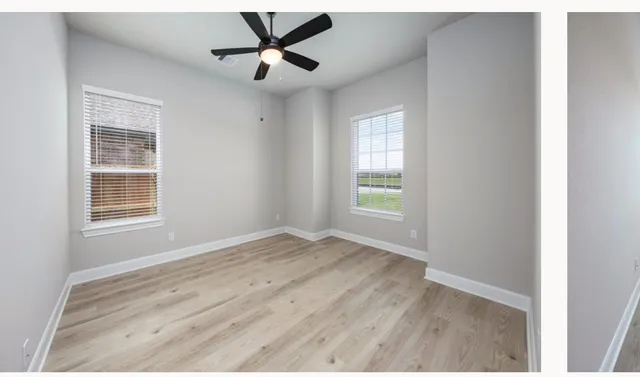a view of empty room with wooden floor and fan