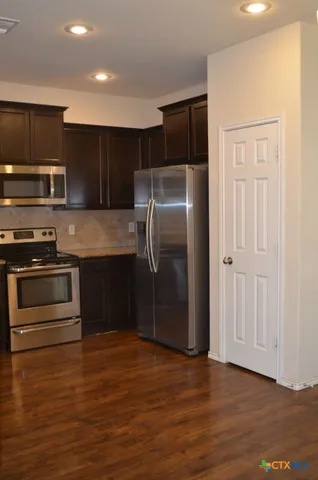 a kitchen with stainless steel appliances granite countertop a refrigerator and a stove top oven