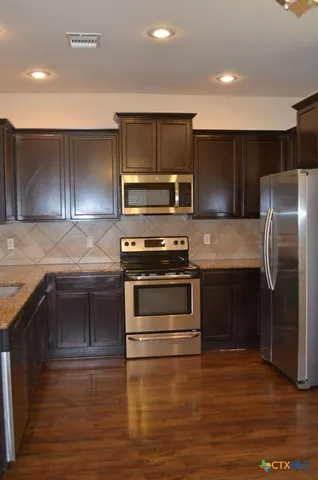a kitchen with kitchen island granite countertop a stove and a refrigerator
