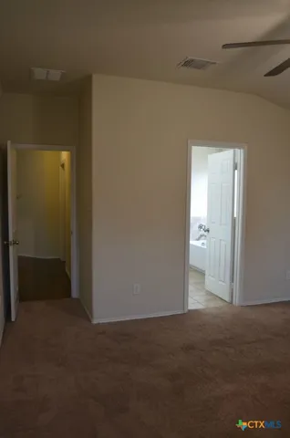 a view of an empty room with wooden floor and a ceiling fan