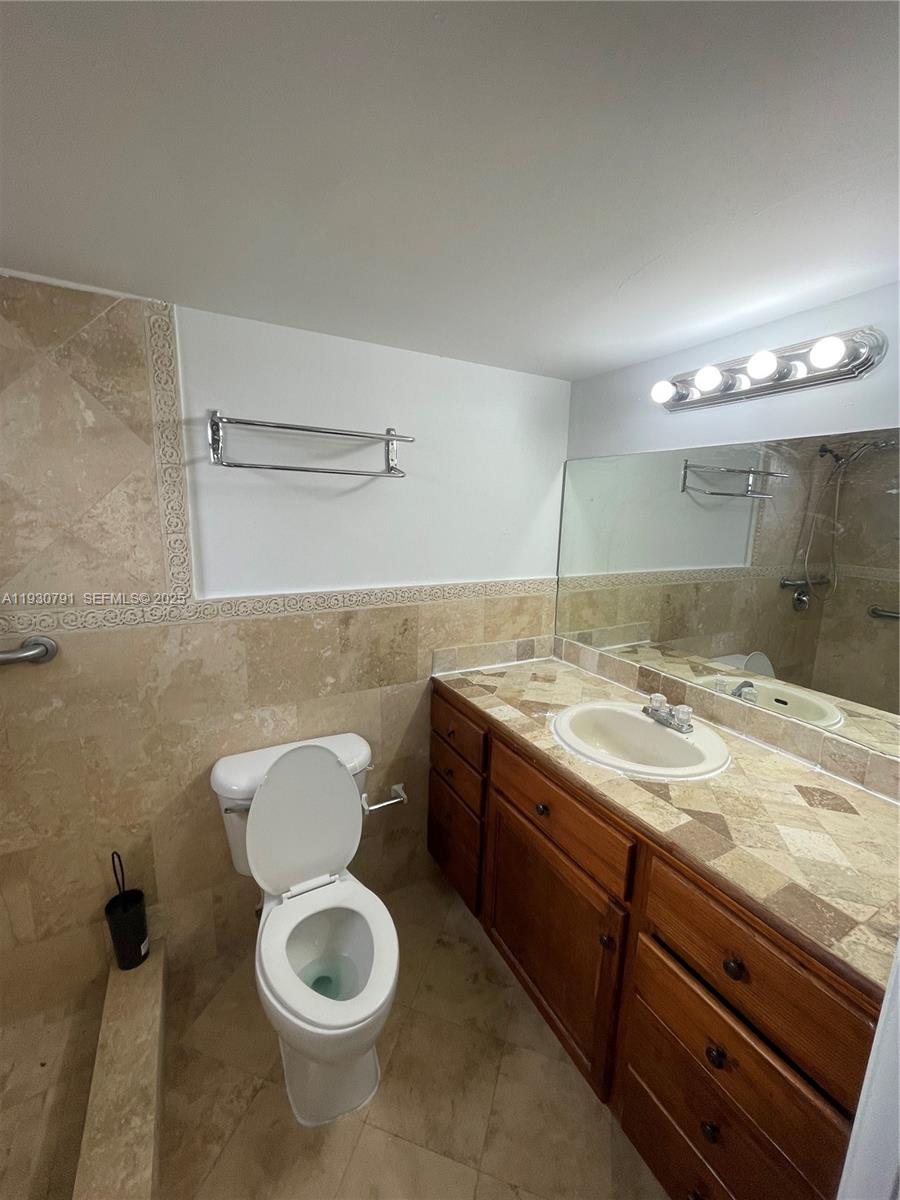 6450 West 27th Way, Unit 101 Hialeah, FL 33016 - Photo 4 of 11 a bathroom with a granite countertop toilet sink and mirror