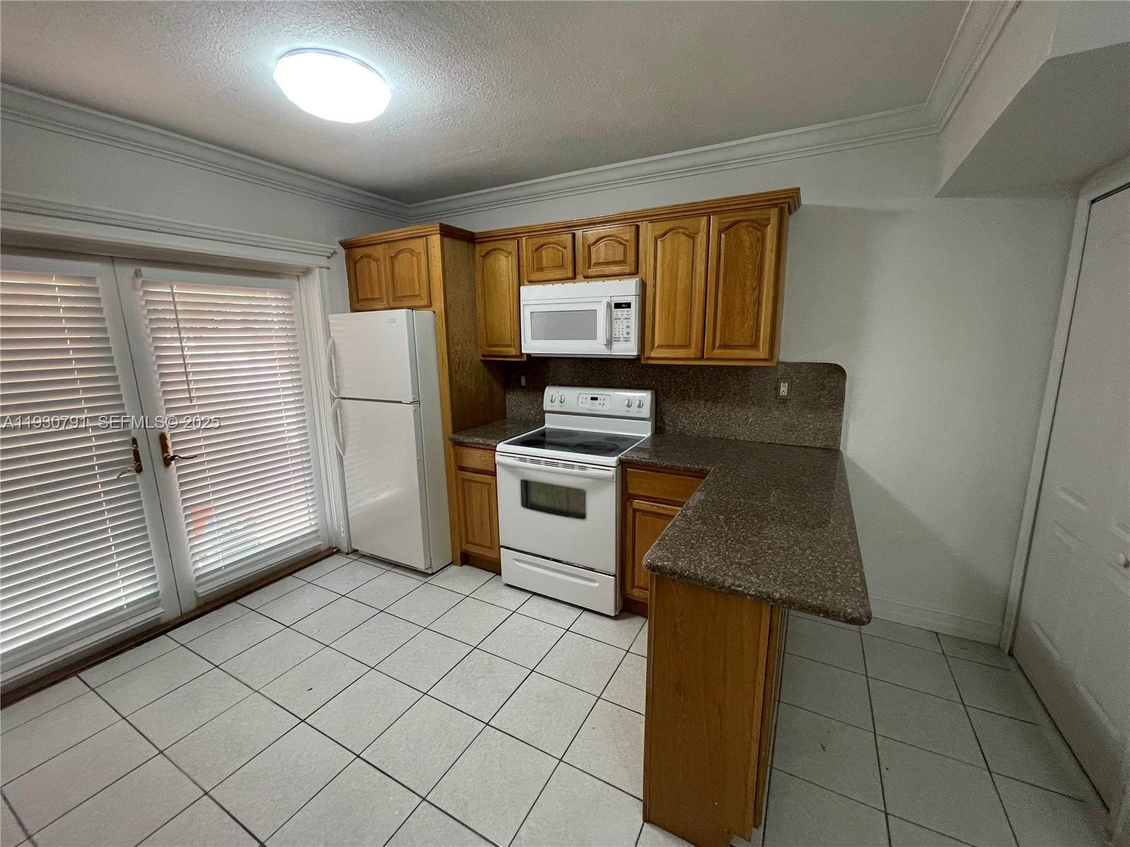 6450 West 27th Way, Unit 101 Hialeah, FL 33016 - Photo 8 of 11 a kitchen with a stove a sink and a refrigerator