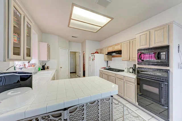 a large kitchen with cabinets appliances and a window