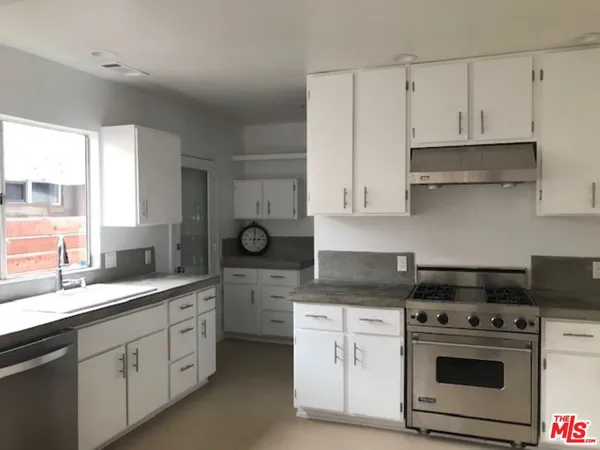 a kitchen with white cabinets and appliances