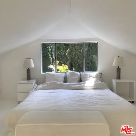 a bedroom with a large window and a bed