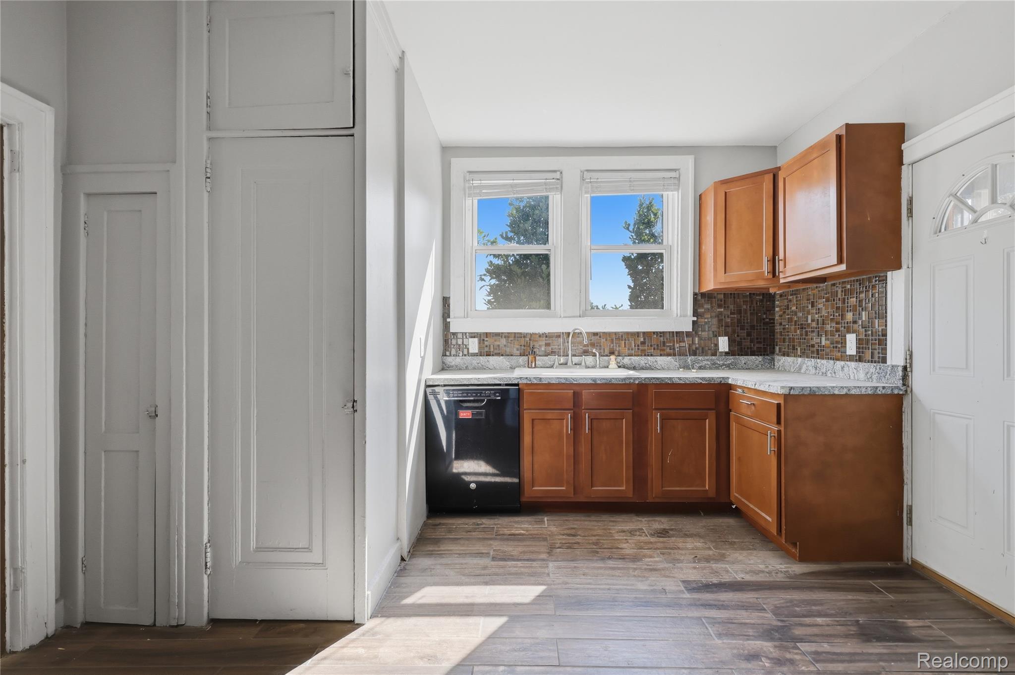 1945 Atkinson Street Detroit, MI 48206 - Photo 21 of 49 Kitchen featuring wood-finish flooring, natural wood cabinetry, light-toned countertops, and a mosaic tile backsplash