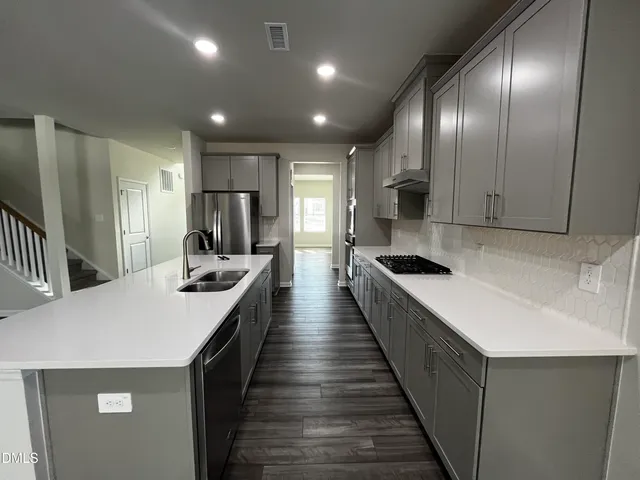 a large kitchen with stainless steel appliances a large counter top a stove a chimney a sink and a refrigerator