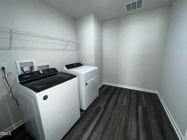 a utility room with wooden floor washer and dryer