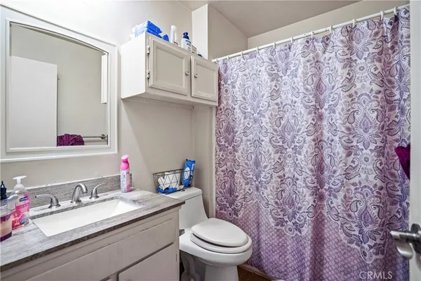 a bathroom with a granite countertop sink and a toilet