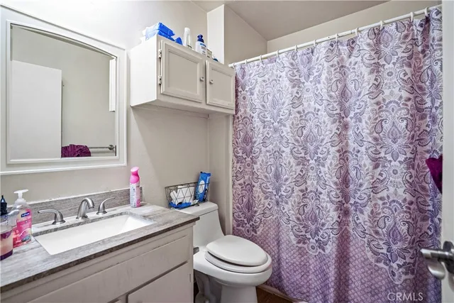 a bathroom with a granite countertop sink and a toilet