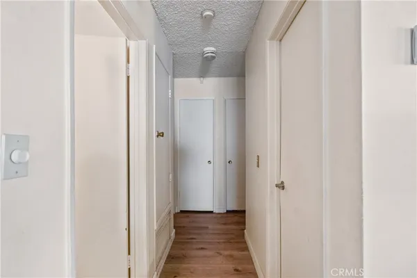 a view of a hallway with wooden floor and a bathroom