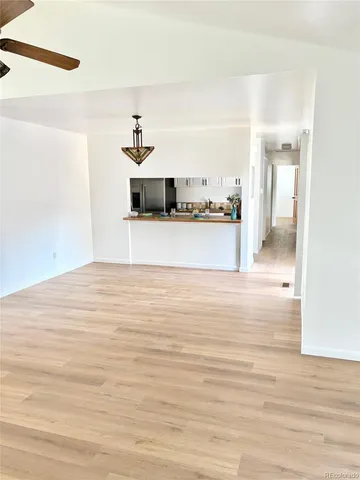 a view of a room with a ceiling fan and hardwood floor