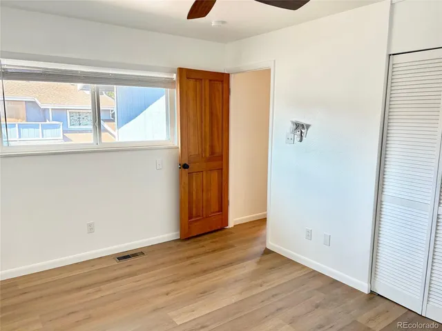 an empty room with wooden floor fan and windows
