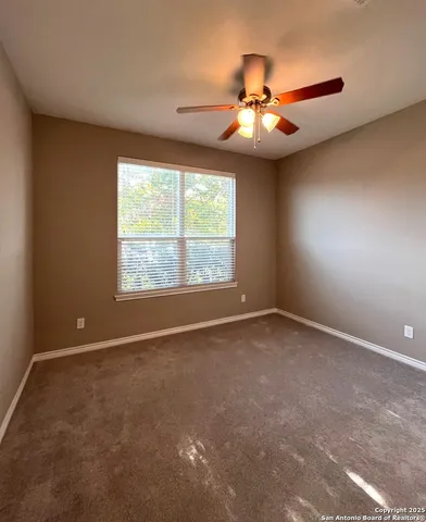 an empty room with a ceiling fan and window