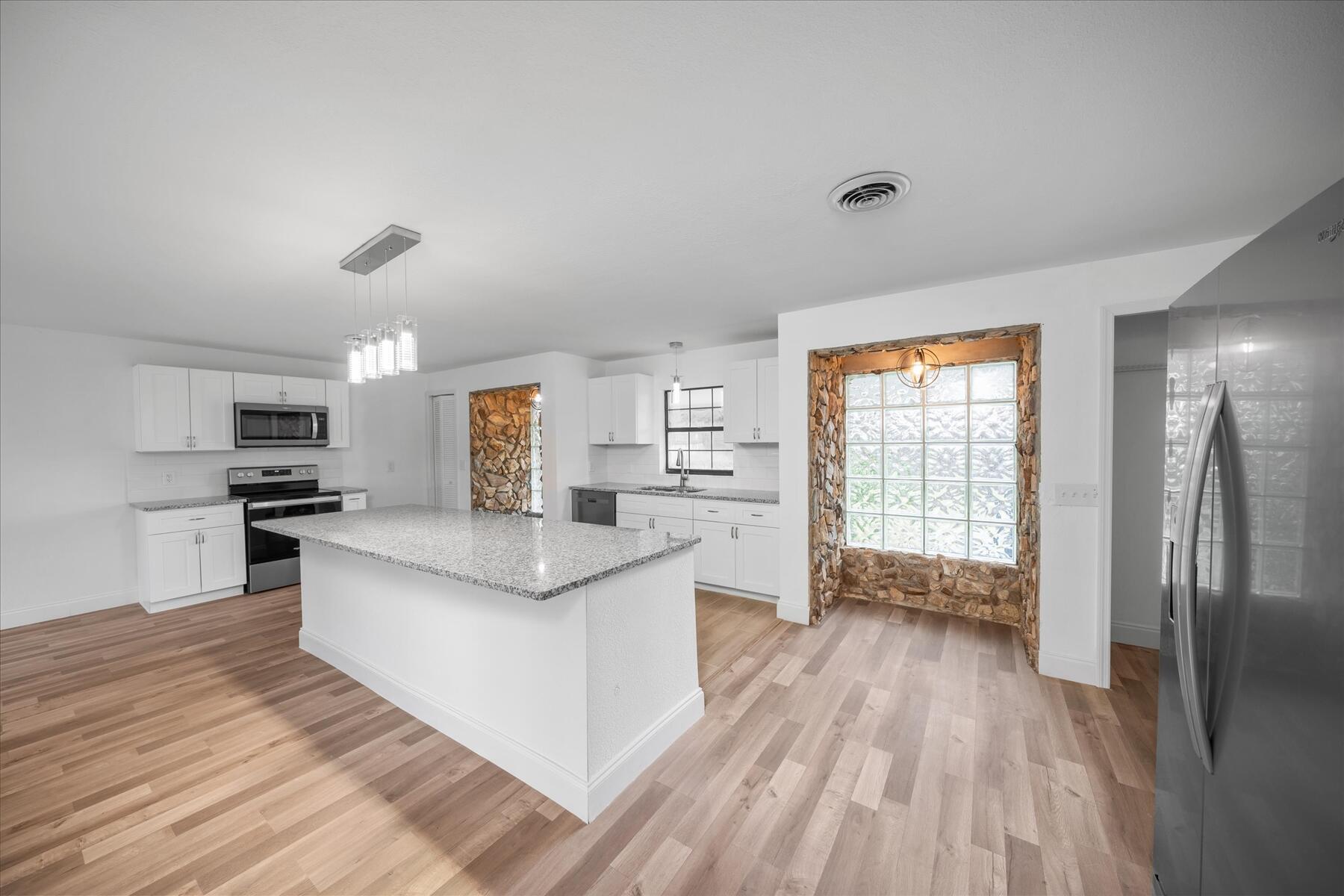 300 East Fee Avenue Melbourne, FL 32901 - Photo 20 of 27 a large white kitchen with wooden floors and stainless steel appliances