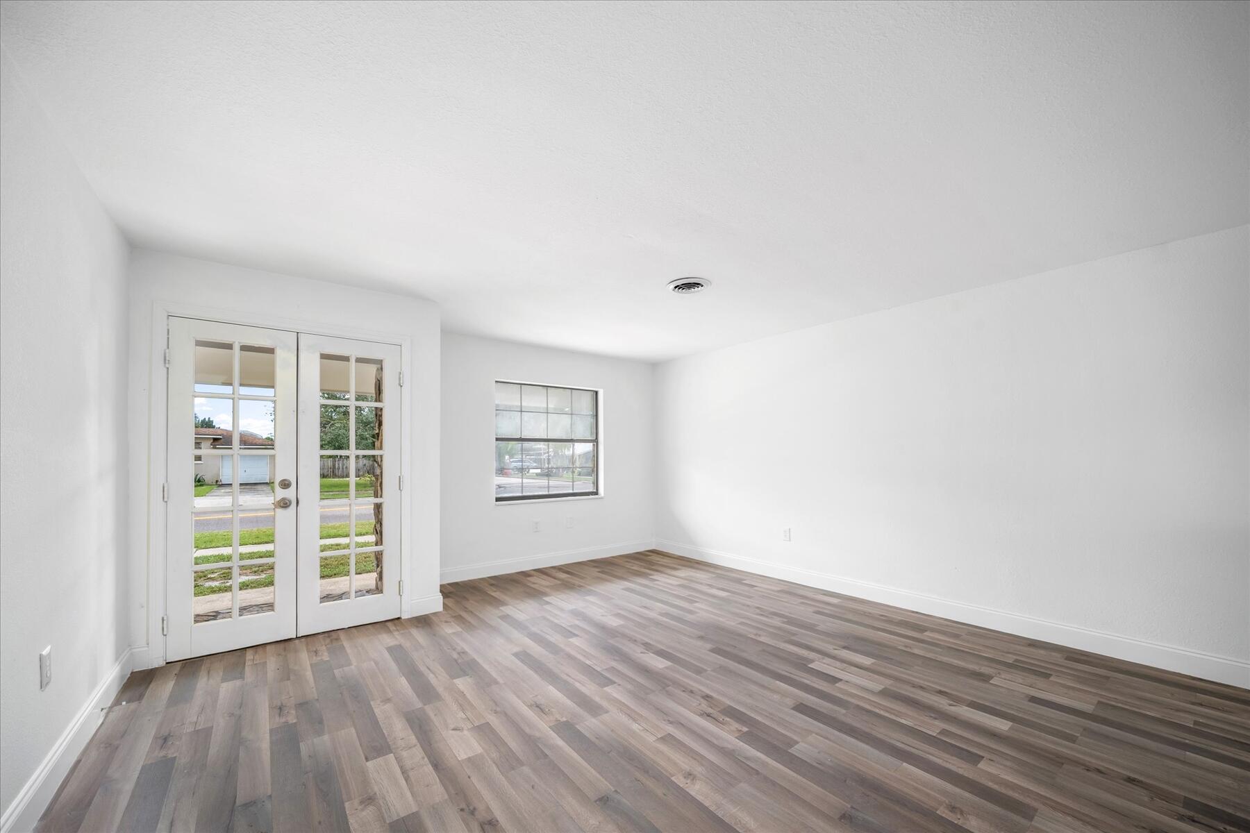 300 East Fee Avenue Melbourne, FL 32901 - Photo 4 of 27 an empty room with wooden floor and windows