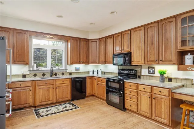 a kitchen with stainless steel appliances granite countertop a refrigerator a sink dishwasher a stove with wooden cabinets and floor