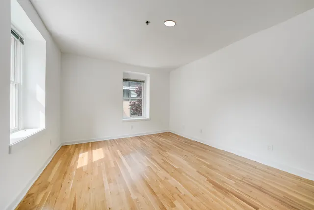 an empty room with wooden floor and windows