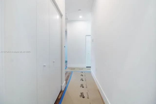 a view of a hallway with wooden floor and a bathroom